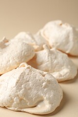 Delicious homemade meringue cookies on beige background, closeup