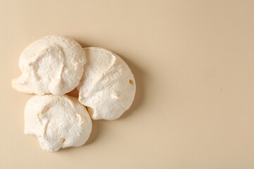 Delicious homemade meringue cookies on beige background, top view. Space for text