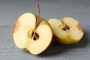 Halves of overripe apple on grey wooden table, closeup