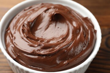 Tasty chocolate pudding in bowl on wooden table, closeup