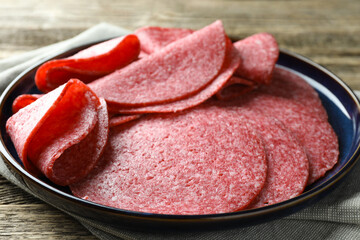 Slices of delicious sausage on wooden table, closeup