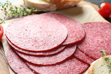 Slices of tasty smoked sausage, tomato, thyme and bread on table, closeup