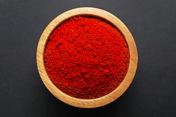 Aromatic red pepper powder in bowl on dark table, top view