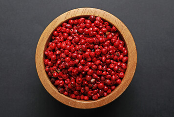 Aromatic peppercorns in bowl on dark table, top view