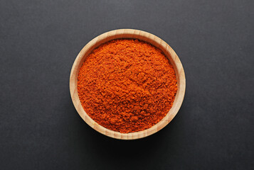 Aromatic paprika powder in bowl on dark table, top view
