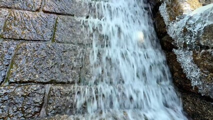 A Serene Waterfall Cascading Gently Over a Beautiful Stone Wall Surrounded by Nature