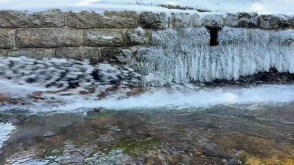 Obraz premium A Frozen Waterfall with an Icy River Flowing Gently Through a Beautiful Wilderness