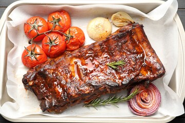 Delicious spare ribs, rosemary, baked onion and sun dried tomatoes in baking tray, top view