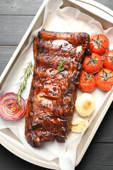 Delicious spare ribs, rosemary, baked onion and sun dried tomatoes on grey wooden table, top view