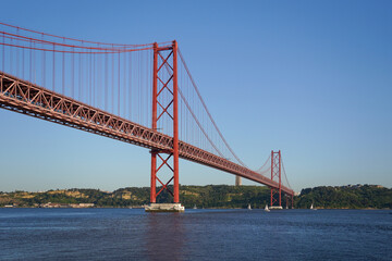 Obraz premium Iconic Red Suspension Bridge over Calm Water Lisbon Portugal The Ponte 25 de Abril suspension bridge
