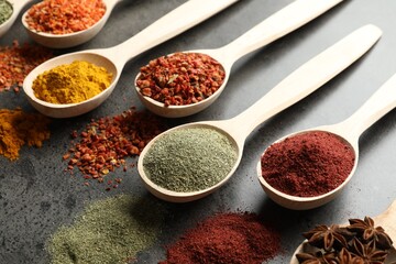 Many different spices in spoons on grey table, closeup
