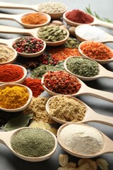 Many different spices in spoons on grey table, closeup