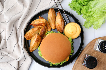 Tasty cheeseburger with sauce and potato wedges on white tiled table, flat lay