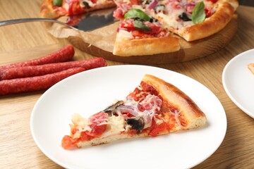 Slice of tasty pizza with thin smoked sausages served on wooden table, closeup