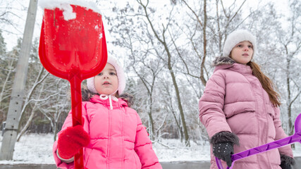 Two little girls playing in a snowy park in winter