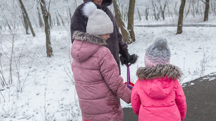 Grandmother with grandchildren in warm clothes playing outdoors in winter park, enjoying snowy...