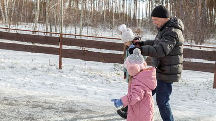Little girls with her grandfather walking in park on snowy winter day