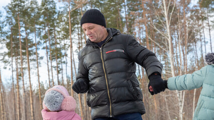 Little girls with her grandfather walking in park on snowy winter day