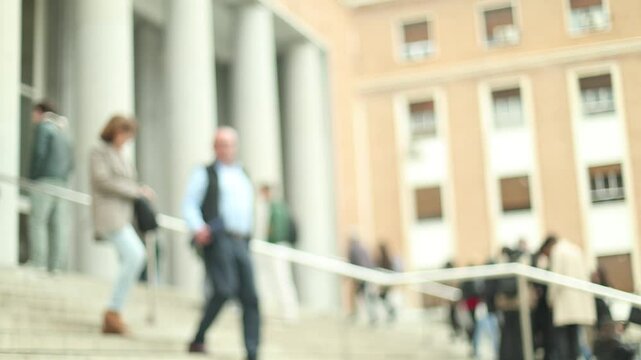 People walking down courthouse steps, blurred background