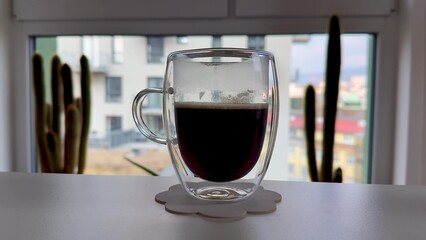A delightful cup of coffee in a stylish glass, set against a vibrant urban backdrop
