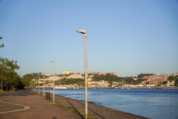Serene Waterfront Promenade Path with Modern Streetlights and City Skyline View