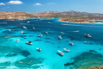 Aerial view of luxury yachts and boats on blue sea, beautiful island, mountain on summer sunny day. Sandy beach, rocky sea coast, azure transparent water in Sardinia, Italy. Top drone view. Seascape