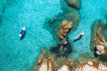 Aerial view of two stand up paddle boards with tourists paddling in the clear turquoise water near...