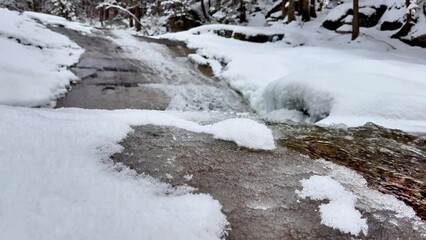 A frozen stream flows through a stunning winter landscape, showcasing natures beauty