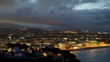 Enjoy a scenic night view of a coastal city with brightly illuminated buildings