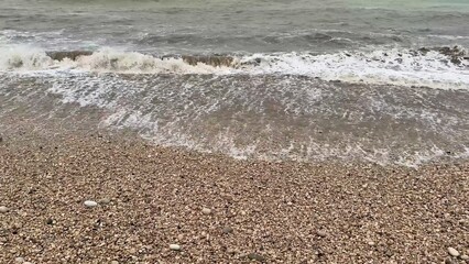 Waves gently crashing on the pebbled beach create a stunningly tranquil seaside scene