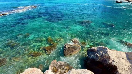 Experience the stunning coastline view featuring crystal clear waters along the rocky shores