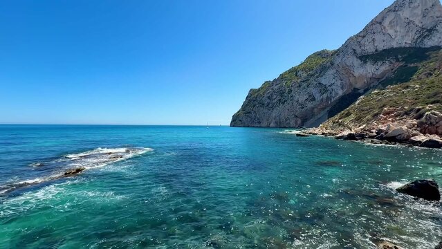 Experience a stunning coastal view featuring clear blue waters alongside majestic rocky cliffs