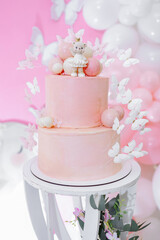 Pink first birthday cake with teddy bear figurine. Soft pastel colors and festive decoration create a warm, festive atmosphere. Sweet cake for a one-year-old birthday girl