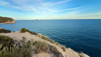 A serene coastal landscape with a clear blue ocean and a sky filled with fluffy clouds