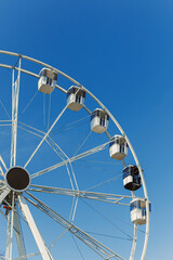 A large Ferris wheel against a blue sky. Cabins on the Ferris wheel.