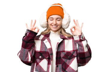 Young  English woman wearing winter muffs over isolated background in zen pose