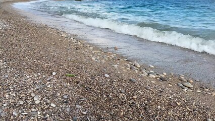 A Beautiful Beach Shoreline with Soft and Gentle Waves Caressing the Pebbles Alongside