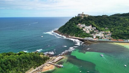Fototapeta premium Stunning Aerial View of a Coastal Town Surrounded by Lush Green Hills and Sparkling Clear Waters