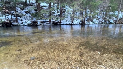 A Serene Stream flowing through a Beautiful Snowy Forest Landscape, ideal for relaxation