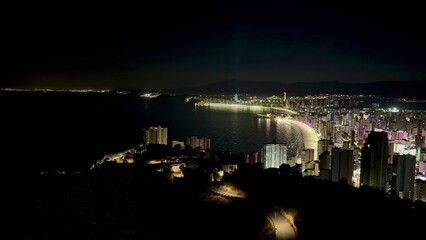 Fototapeta premium Experience the stunning nightscape of a coastal city with its beautifully illuminated skyline
