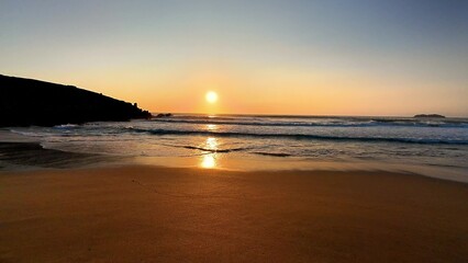 A serene beach sunset, where gentle waves meet a tranquil horizon, creates a picturesque scene