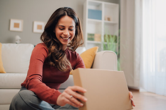 Happy woman opening a package at home