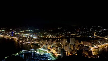 Naklejka premium The stunning night view of a coastal city features beautifully illuminated, sparkling buildings