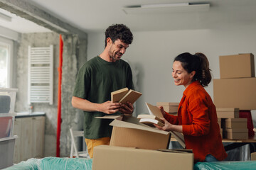 Obraz premium Happy couple unpacking books in new home during renovation