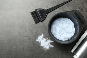 Bowl with hair bleaching powder, foil and brush on grey table, flat lay. Space for text