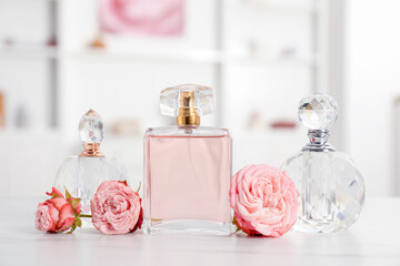 Bottles of perfume and beautiful flowers on white table