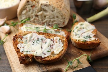 Tasty bread with garlic, herbs and oil on wooden table, closeup