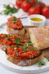 Tasty bread with tomatoes, parsley and oil on table, closeup