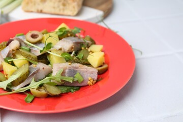 Delicious salad with herring on white tiled table, closeup
