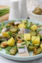 Delicious salad with herring and ingredients on white table, closeup